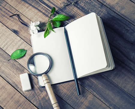 Blank notepad, magnifier, pencil and eraser on wooden background.の写真素材
