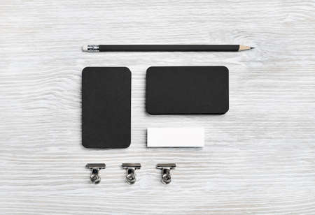 Blank black business cards, pencil and eraser on light wooden background. Branding ID mockup. Top view. Flat lay.の写真素材