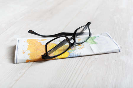 Glasses and map on a wooden background.