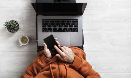 Work at home. Laptop and smartphone in the hands of a man. Businessman or freelancer at work sits on...