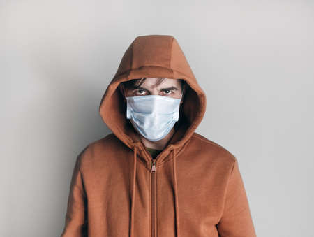 Man in a medical mask and brown hoodie. Stay at home. Virus protection.の写真素材