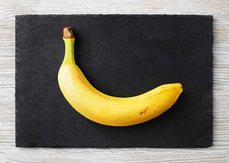 Delicious ripe banana on stone board. Flat lay.の写真素材