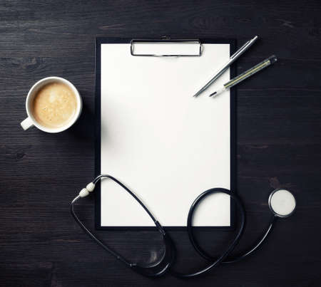 Doctor's medical supplies. Blank clipboard, stethoscope, badge, thermometer, pen and coffee cup on...