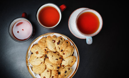 Oatmeal cookies with raisins and tea cups on black table. flat lay.の写真素材