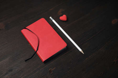 Photo of blank red notebook, pencil and heart-shaped eraser on wooden background.の写真素材