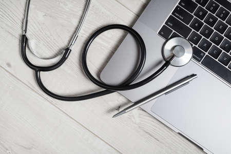 Stethoscope, laptop keyboard and pen on wooden background. top view. flat lay.の写真素材