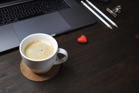 Coffee break concept. Coffee cup, laptop, heart-shaped eraser and pencils on wooden background. selective focus.の写真素材
