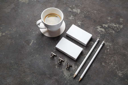 Branding mockup. Photo of blank business cards, pencils, coffee cup and clips on concrete...