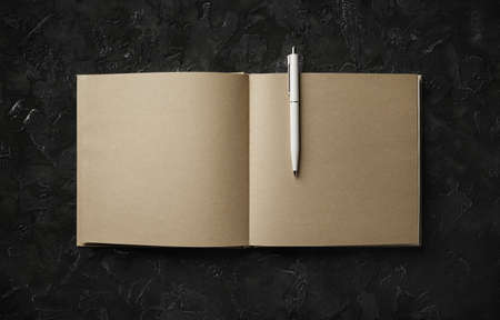 Blank craft paper book and pen on black stone background. Responsive design mockup. flat lay.