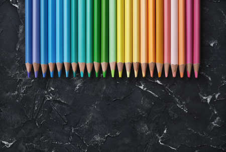 Row of colorful pencils on black plaster background. Top view with copy space. flat lay.の写真素材