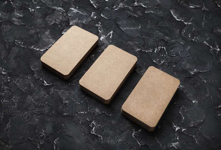 Blank kraft business cards on black plaster background. Mockup for branding identity. Template for graphic designers portfolios.の写真素材