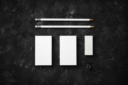 Blank business cards, pencils and eraser on black plaster background. Blank stationery template. top view. flat lay.の写真素材