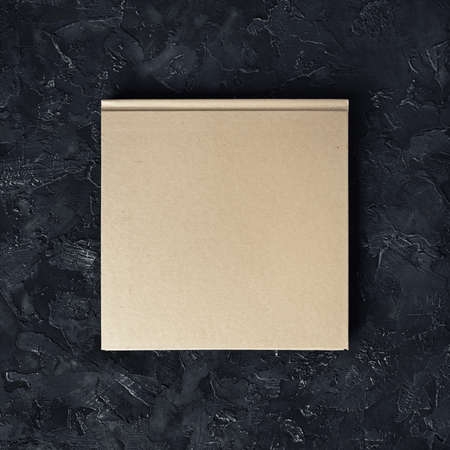 Closed blank square booklet on black plaster background. top view.の写真素材