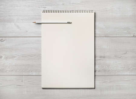 Photo of blank notepad and pencil on light wooden background. Responsive design template. flat lay.