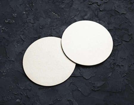 Blank white beer coasters on black plaster background.の写真素材