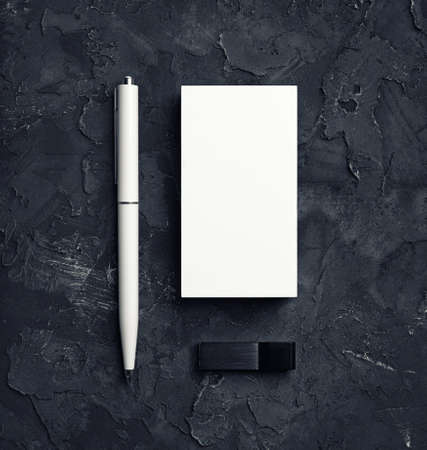 Blank business cards, pen and usb flash drive on black plaster background. Responsive design template. top view.の写真素材