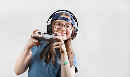 Teen girl in headphones plays video games with a gamepad in her hands. gamer girl.の写真素材