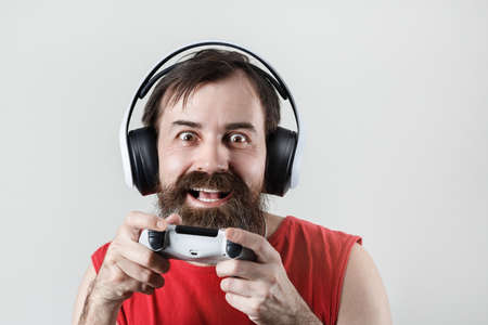 Happy bearded man in headphones and with a gamepad in his hands. gamer plays video games.の写真素材