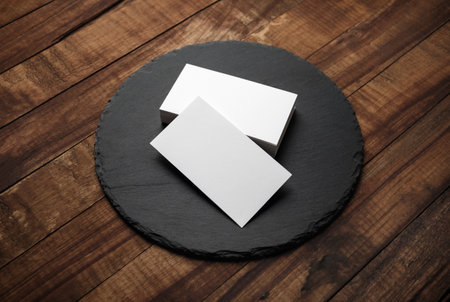 Blank white business cards and round slate plate on wooden background. Mockup for branding identity.の写真素材