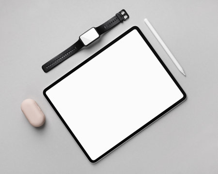 Tablet computer with blank white screen, fitness bracelet and stylus pen on gray paper background. top view. flat lay.の写真素材