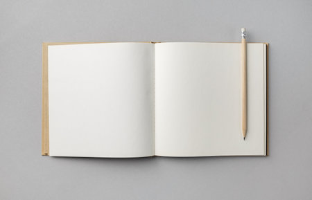 Blank open book or brochure and pencil on gray paper background. Responsive design mockup. flat lay.の写真素材