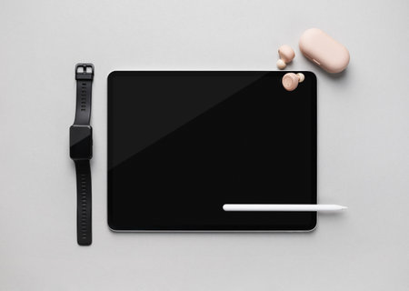 Modern digital tablet, stylus pen, smartwatch and headphones on gray paper background. Responsive design mockup. top view. flat lay.の写真素材