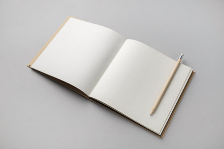 Blank open sketchbook and pencil on gray paper background. Responsive design template.の写真素材