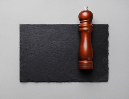 Photo of pepper mill and slate plate on gray paper background. copyspace. flat lay.の写真素材