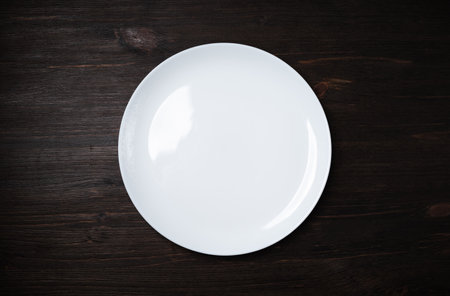 Blank white dish on dark wooden background. flat lay.の写真素材