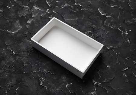 Blank white opened box on black plaster background.