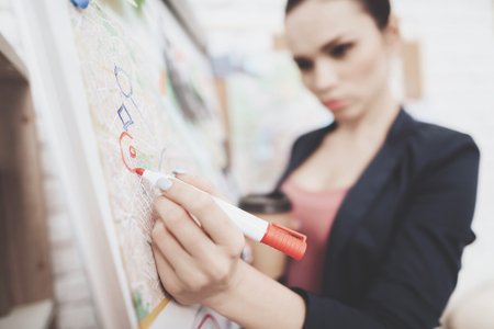 Private detective agency. Woman in jacket is putting photos marks with marker on clue map in office.の写真素材