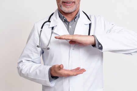 Portrait of doctor in white gown with stethoscope holding hands isolated.の写真素材