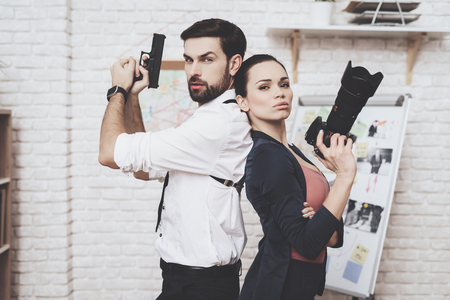 Private detective agency. Woman is posing with camera, man with holster is posing with gun.の写真素材