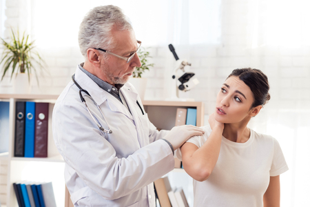 Doctor in white gown with stethoscope and female patient in office. Doctor is examining woman's back.の写真素材