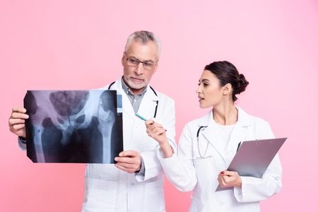 Portrait of male and female doctors in white gowns with stethoscopes holding x-ray and clipboard isolated.の写真素材