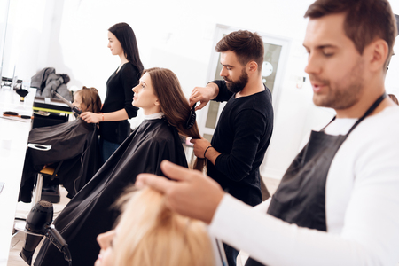 Hairdressers make haircut for women of different age categories in beauty salon. Grandmother, mother and daughter in beauty salon.の写真素材