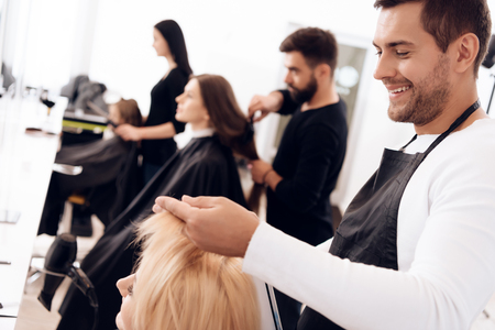 Hairdressers make haircut for women of different age categories in beauty salon. Grandmother, mother and daughter in beauty salon.の写真素材