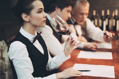 Experienced sommelier woman explores taste of wine in restaurant. Wine tasting. Checking taste, color, sediments of wine.の写真素材