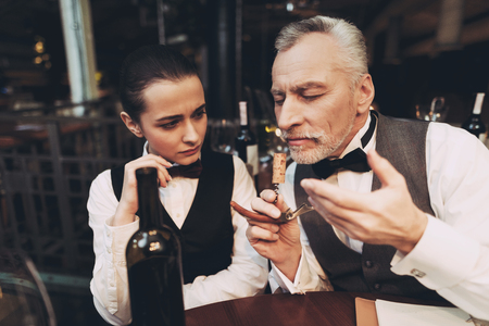 Experienced sommelier tastes aroma of wine from cork on corkscrew in restaurant. Wine tasting. Professional degustation expert in winemaking.の写真素材