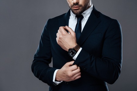 Close-up handsome and successful man in an expensive suit. He is in a white shirt with a tie. A...