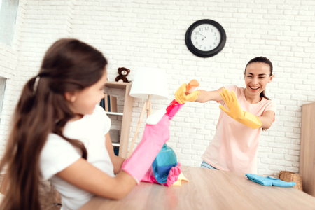 Mom and daughter are cleaning at home. They fool around and squirt with detergents. they are having fun.の写真素材