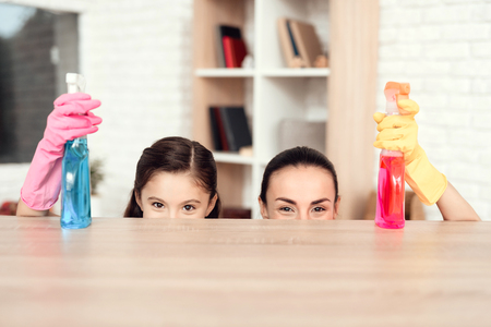 A woman and a girl are posing with money for cleaning the apartment. They are at home. Behind them...