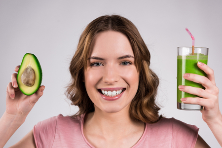 Girl posing with green juice and avocado isolated on white background.の写真素材