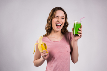 Girl posing with green juice and banana isolated on white background.の写真素材