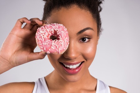 African American girl holding donut isolated on white background.の写真素材