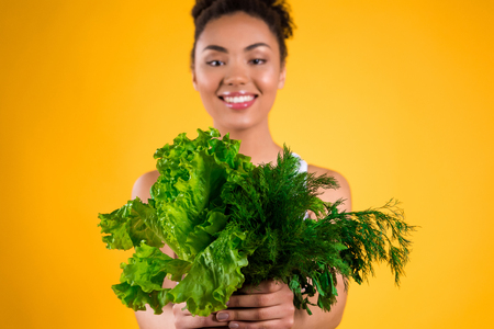 African American girl holding salad isolated on yellow background.の写真素材
