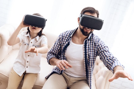 Father and son, using virtual reality glasses, play an interactive game. Future Technology Concept.の写真素材