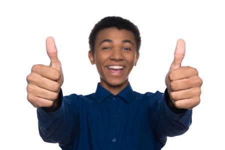 Joyful Afro American teen showing thumbs up. Isolated on white background. Studio portrait. Transitional age concept.の写真素材
