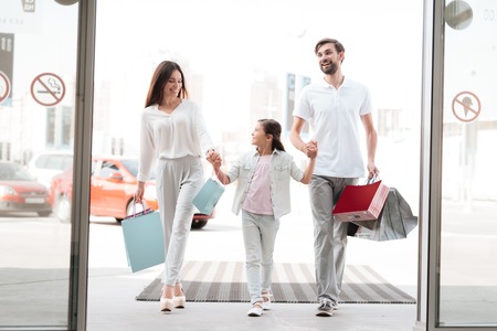 Family, father, mother and daughter with shopping bags are entering shopping mall.の写真素材