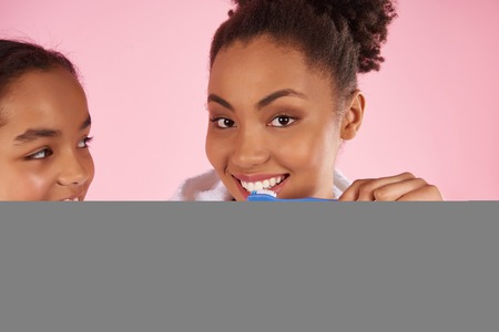 Happy black mother and daughter in dressing gown brush teeth. Dental hygiene concept. Isolated on...